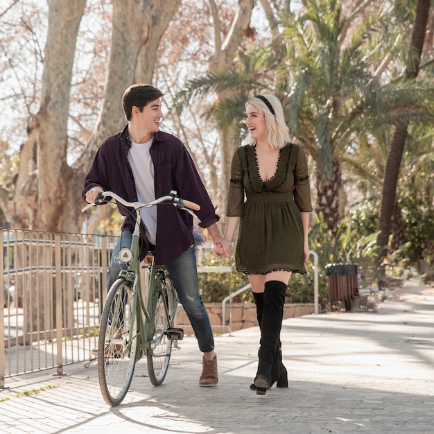 Foto gratuita hermosa pareja en el parque con bicicleta