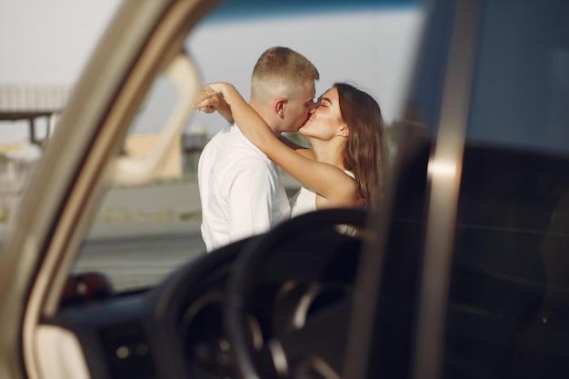 Hermosa pareja pasa tiempo en un parque de verano cerca de un automóvil