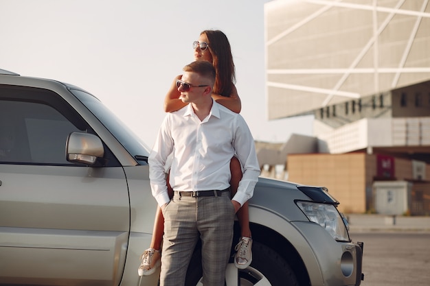 Hermosa pareja pasa tiempo en un parque de verano cerca de un automóvil