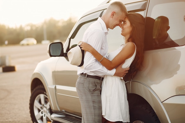 Foto gratuita hermosa pareja pasa tiempo en un parque de verano cerca de un automóvil