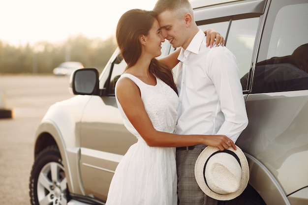 Hermosa pareja pasa tiempo en un parque de verano cerca de un automóvil