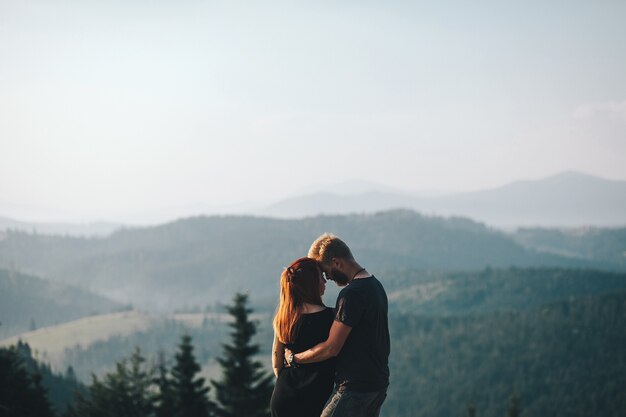 Hermosa pareja de pie sobre una montaña y mirando el uno al otro