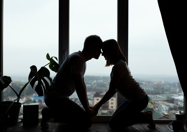 Hermosa pareja posando junto a la ventana