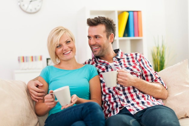 Hermosa pareja relajándose en el sofá con una taza de café