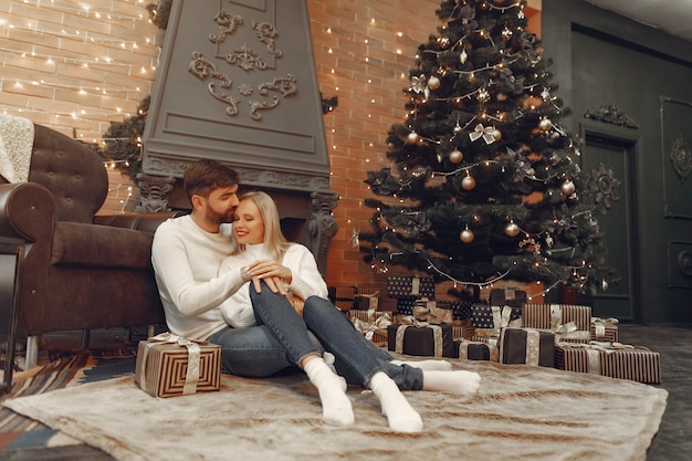 Hermosa pareja sentada en casa cerca del árbol de navidad