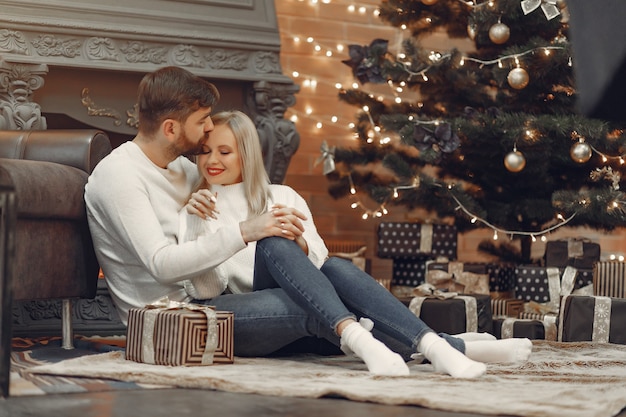 Hermosa pareja sentada en casa cerca del árbol de navidad