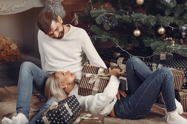 Hermosa pareja sentada en casa cerca del árbol de navidad