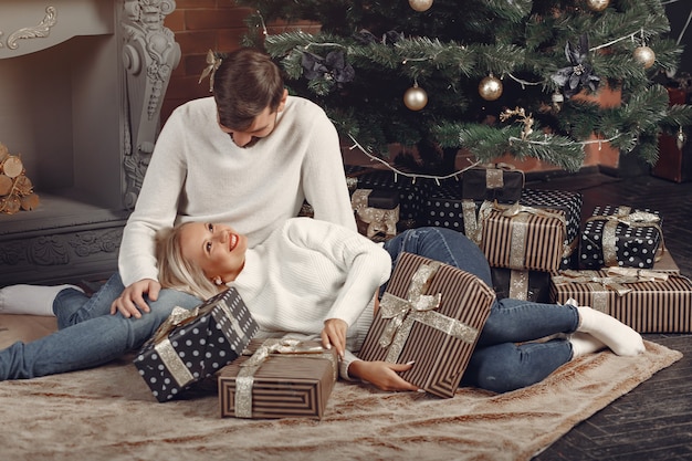 Hermosa pareja sentada en casa cerca del árbol de navidad