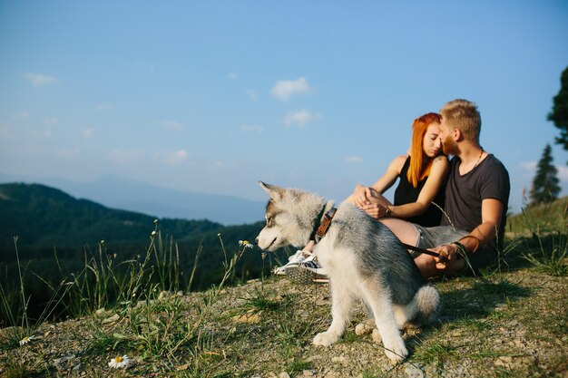 Hermosa pareja se sienta en una colina y abrazándose