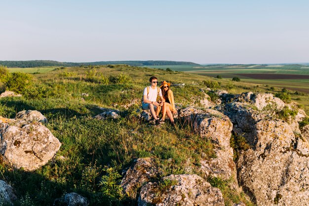 Hermosa pareja sonriente relajante en roca después de ir de excursión