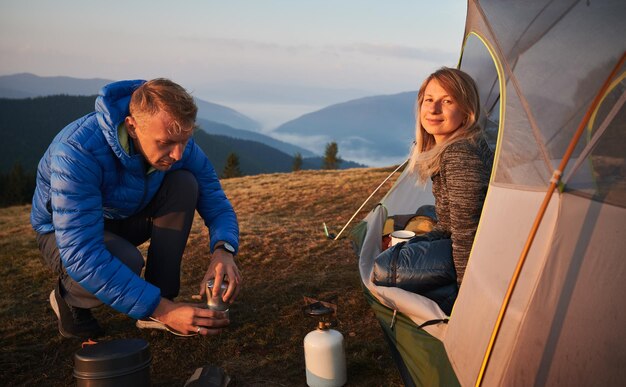 Hermosa pareja de viajeros acampando en las montañas