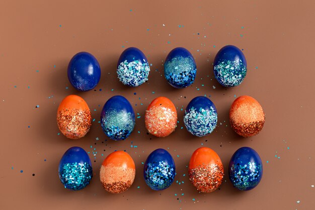 Hermosa Pascua con huevos decorativos naranjas y azules en lentejuelas.