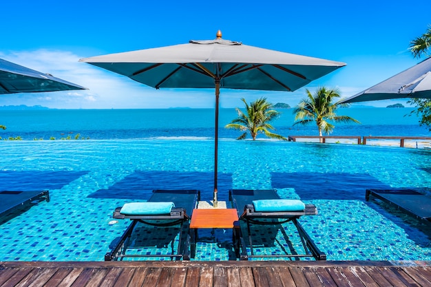 Foto gratuita hermosa piscina de lujo al aire libre en el complejo hotelero con mar océano alrededor de palmera de coco y nube blanca en el cielo azul