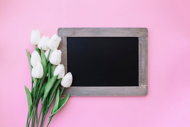 hermosa pizarra para maqueta con bonitos tulipanes sobre fondo rosa