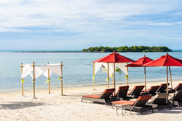 Hermosa playa tropical al aire libre mar océano con silla sombrilla y lounge deck alrededor de allí en el cielo azul nube blanca