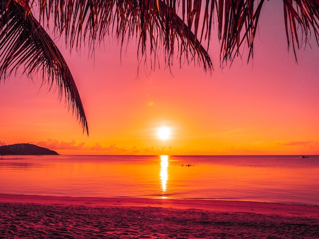 Hermosa playa tropical mar y océano con palmera de coco en el momento de la salida del sol