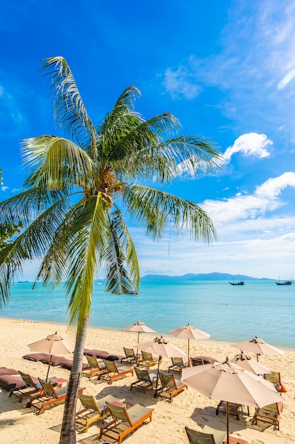 Foto gratuita hermosa playa tropical mar y océano con palmera de coco y sombrilla y silla en cielo azul