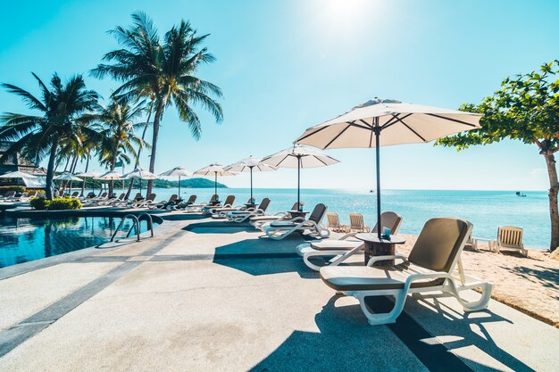 Hermosa playa tropical y mar con sombrilla y silla alrededor de la piscina.