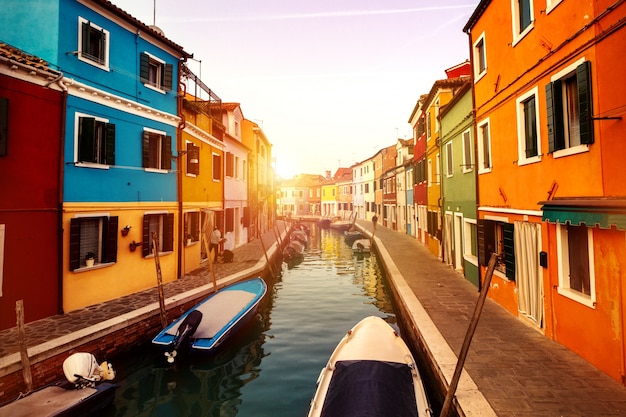 Hermosa puesta de sol con barcos, edificios y agua. Luz de sol. Viraje. Burano, Italia.