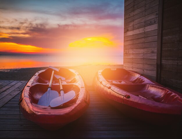 La hermosa puesta de sol con par de Kayak barco rojo con sol.