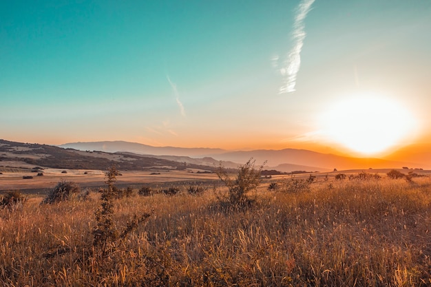 Hermosa puesta de sol sobre los campos y las montañas.