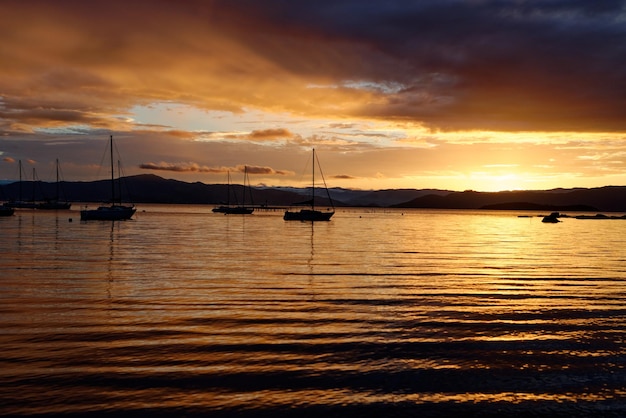 Hermosa puesta de sol en tonos naranja con siluetas de barcos en Santo Antonio de Lisboa, Florianópolis, Brasil