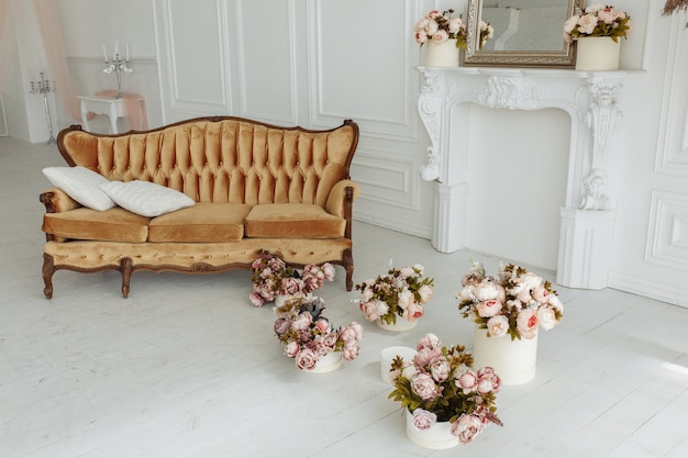Hermosa sala de estar de Provance con sofá marrón junto a la chimenea con flores y velas