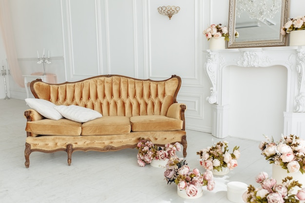 Hermosa sala de estar provenzal con sofá vintage marrón Cerca de la chimenea con flores y velas