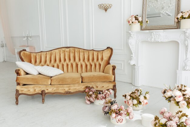Hermosa sala de estar provenzal con sofá vintage marrón Cerca de la chimenea con flores y velas