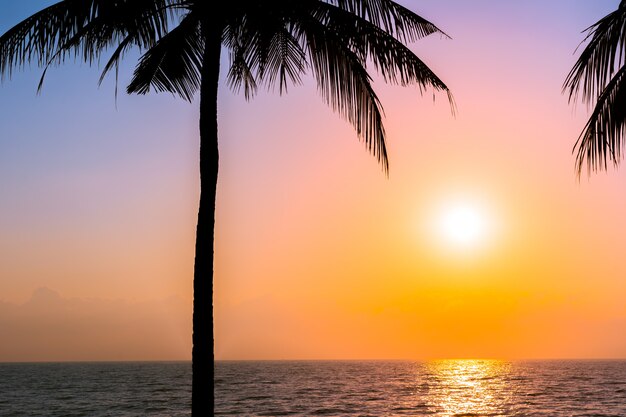 Hermosa silueta de palmera de coco en el cielo de la playa del océano cerca del mar al atardecer o al amanecer