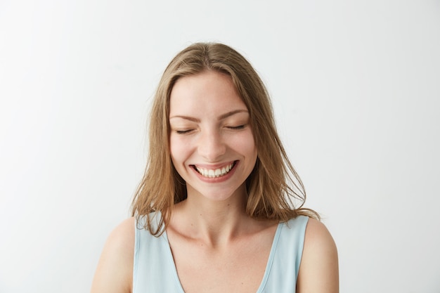 Hermosa sincera alegre alegre niña sonriente riendo con los ojos cerrados.