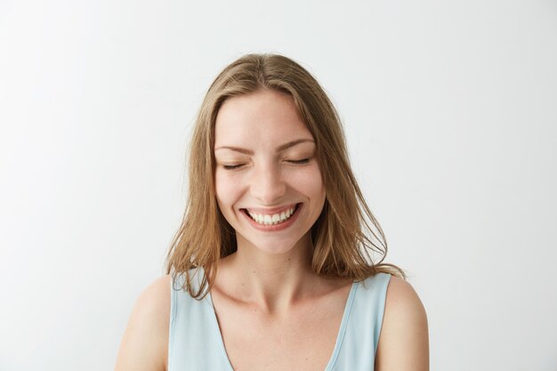 Hermosa sincera alegre alegre niña sonriente riendo con los ojos cerrados.