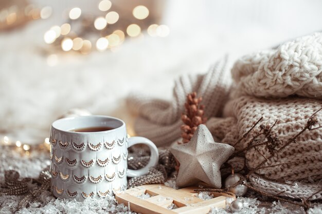 Hermosa taza de Navidad con una bebida caliente sobre un fondo borroso claro. El concepto de confort y calidez en el hogar.