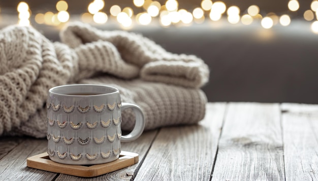 Hermosa taza de navidad y elemento de punto sobre fondo borroso con bokeh