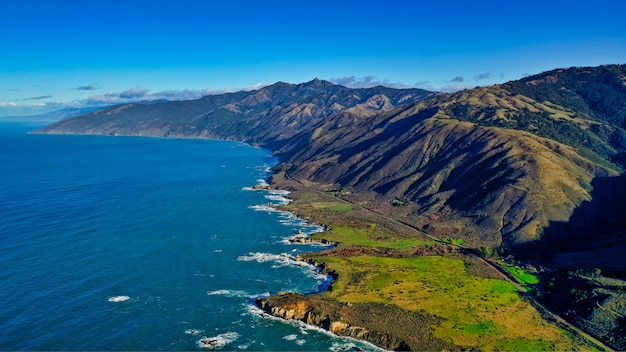 Hermosa toma aérea de la costa del mar con hojas verdes y cielo nublado increíble