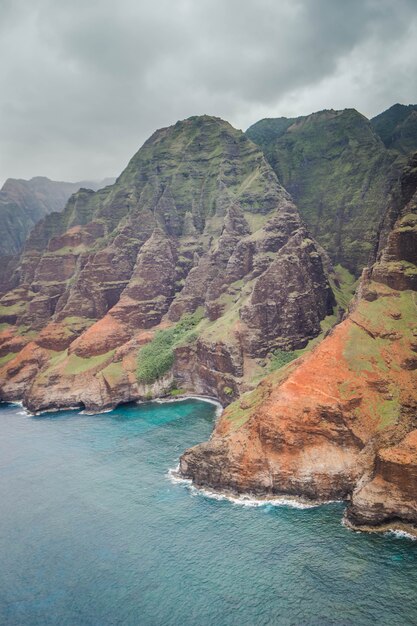 Hermosa toma aérea de la costa de Napali con agua clara y rocas empinadas