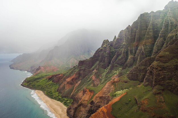 Hermosa toma aérea de la costa de Napali con agua clara y rocas empinadas