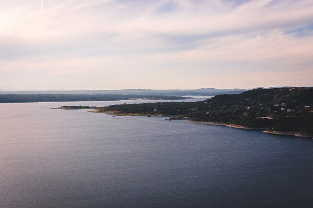 Hermosa toma aérea de un lago con un campo verde en el lateral