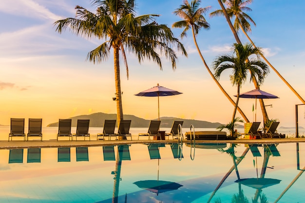 Hermosa vista al aire libre con sombrilla y silla alrededor de la piscina en un hotel de lujo