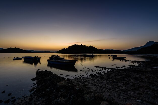 Hermosa vista de los barcos por la orilla bajo la puesta de sol en el cielo