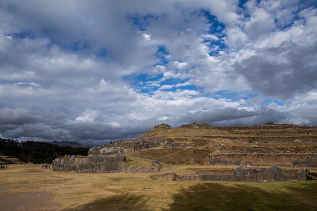 Foto gratuita hermosa vista de los campos cubiertos de hierba y acantilados bajo las increíbles nubes en el cielo