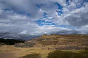 Foto gratuita hermosa vista de los campos cubiertos de hierba y acantilados bajo las increíbles nubes en el cielo