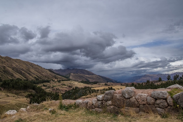 Foto gratuita hermosa vista de los campos en las montañas bajo el cielo nublado capturado en cusco, perú