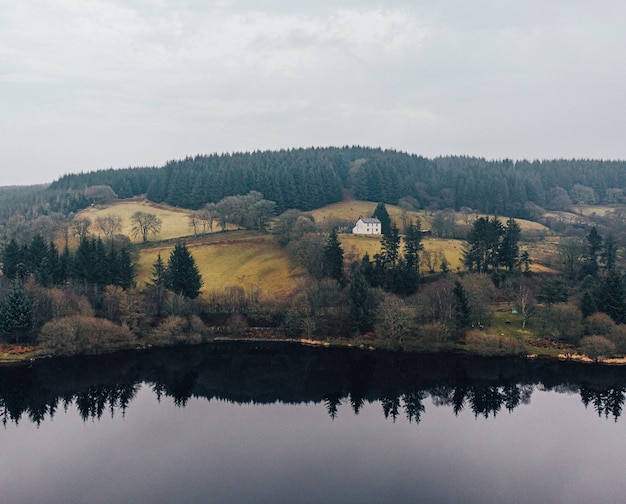 Hermosa vista de una casa cerca de un lago rodeado de árboles en un bosque