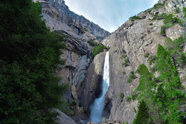 Hermosa vista de una cascada que fluye de una roca y se vierte en el magnífico paisaje verde