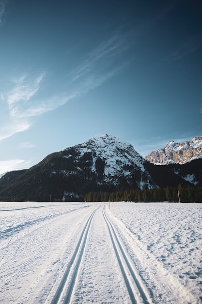 Hermosa vista del cielo azul con montañas y una carretera nevada con huellas de neumáticos durante el invierno