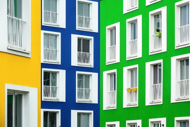 Hermosa vista de edificios de apartamentos en colores brillantes con ventanas de marco blanco en un día fresco