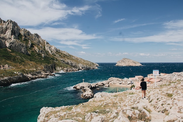 Hermosa vista de enormes rocas y mar tranquilo con una mujer joven deambulando, Marsella, Francia