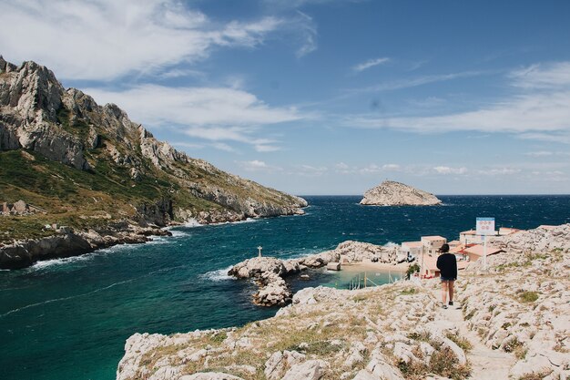Hermosa vista de enormes rocas y mar tranquilo con una mujer joven deambulando, Marsella, Francia