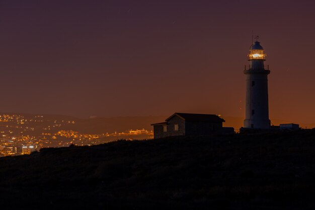 Hermosa vista de un faro y una casa en una colina capturada por la noche en Chipre